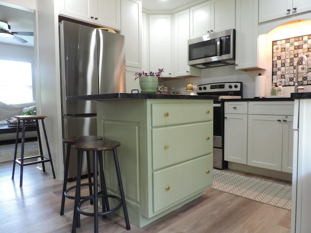87 Lawrence Dr, Ringgold, GA 30736 - kitchen featuring appliances with stainless steel finishes, light wood finished floors, dark countertops, ceiling fan, and white cabinets