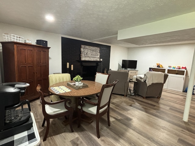 87 Lawrence Dr, Ringgold, GA 30736 - dining space featuring wood finished floors, a textured ceiling, and a brick fireplace