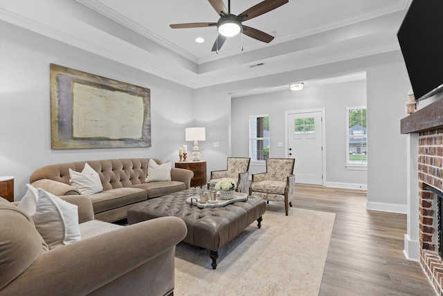 3339 Stone Creek Dr, Chattanooga, TN 37405 - living room featuring a brick fireplace, a ceiling fan, wood finished floors, ornamental molding, and a raised ceiling