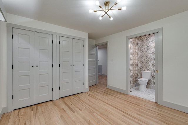 395 Robinson Ln, Decatur, TN 37322 - unfurnished bedroom with two closets, a chandelier, wood finished floors, and ensuite bathroom