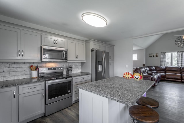 9600 Lovell Rd, Soddy Daisy, TN 37379 - kitchen featuring appliances with stainless steel finishes, gray cabinetry, open floor plan, decorative backsplash, and a breakfast bar area
