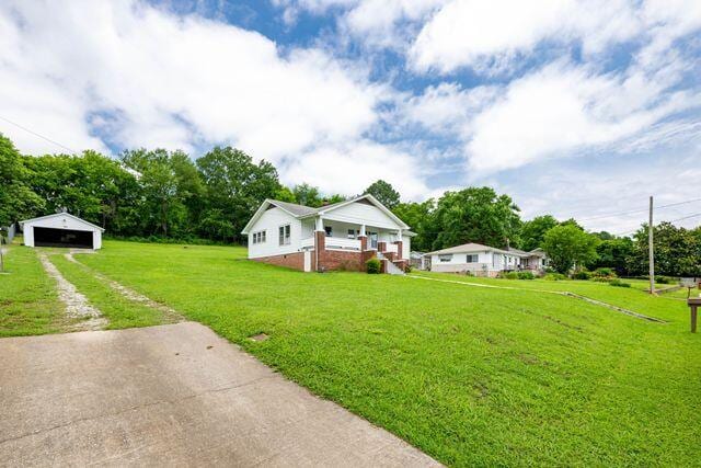 3313 Harrison Pike, Chattanooga, TN 37416 - view of front facade featuring a detached garage, driveway, an outbuilding, a front lawn, and a porch
