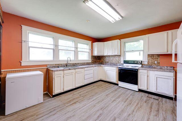 3313 Harrison Pike, Chattanooga, TN 37416 - kitchen featuring white electric range oven, white cabinetry, light wood finished floors, and plenty of natural light