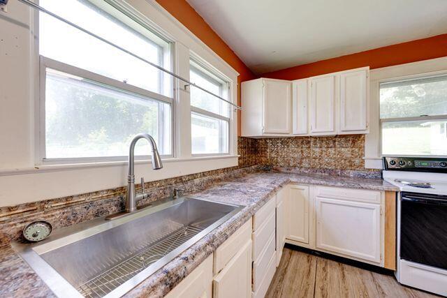 3313 Harrison Pike, Chattanooga, TN 37416 - kitchen with white electric stove, white cabinetry, plenty of natural light, and light wood-type flooring