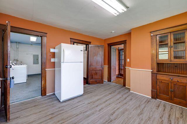 3313 Harrison Pike, Chattanooga, TN 37416 - kitchen featuring freestanding refrigerator, light wood-style floors, electric panel, brown cabinetry, and wainscoting