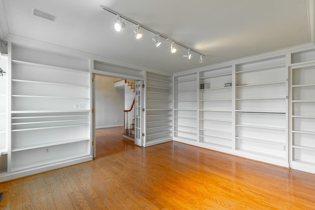 11216 Ooltewah Georgetown Rd, Georgetown, TN 37336 - spare room with rail lighting, stairs, built in shelves, and wood finished floors