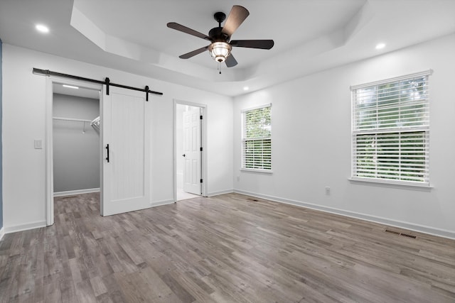 651 Howard Leonard Rd, Ringgold, GA 30736 - unfurnished bedroom featuring a barn door, a raised ceiling, wood finished floors, a walk in closet, and recessed lighting
