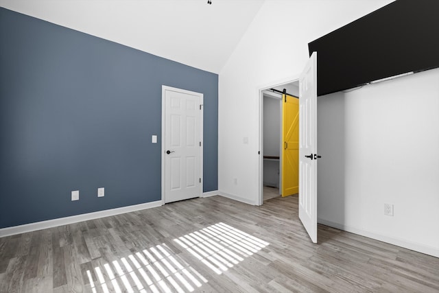 651 Howard Leonard Rd, Ringgold, GA 30736 - unfurnished bedroom with wood finished floors, a barn door, and high vaulted ceiling