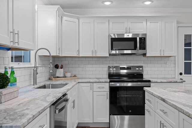 8512 Creek Stone Dr, Chattanooga, TN 37421 - kitchen with appliances with stainless steel finishes, crown molding, white cabinets, light stone counters, and decorative backsplash