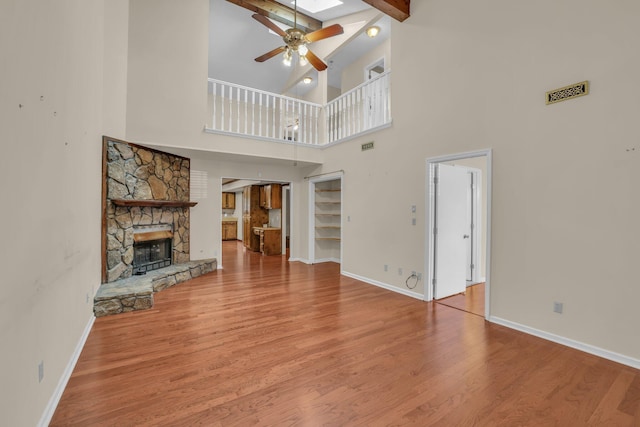 1259 Leaside Ln, Hixson, TN 37343 - unfurnished living room featuring ceiling fan, a stone fireplace, high vaulted ceiling, beamed ceiling, and wood finished floors