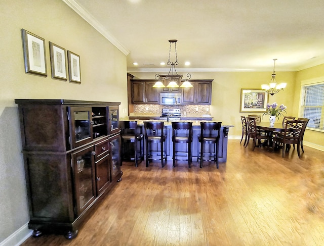 179 Trade Wind Dr, Fort Oglethorpe, GA 30742 - kitchen with appliances with stainless steel finishes, dark wood finished floors, a chandelier, a breakfast bar area, and backsplash