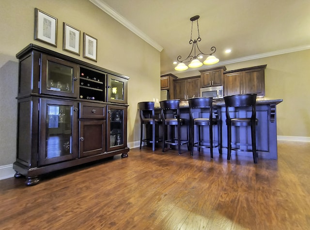 179 Trade Wind Dr, Fort Oglethorpe, GA 30742 - kitchen featuring stainless steel microwave, dark wood-style floors, ornamental molding, a kitchen breakfast bar, and dark brown cabinetry
