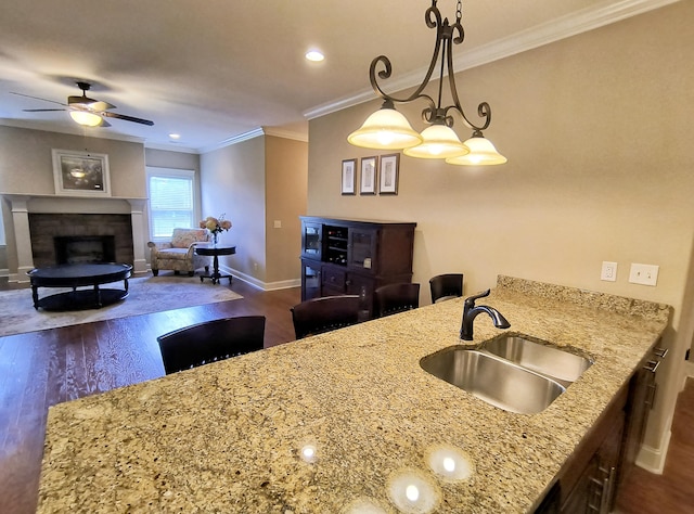 179 Trade Wind Dr, Fort Oglethorpe, GA 30742 - kitchen featuring dark wood finished floors, a ceiling fan, light stone counters, ornamental molding, and a fireplace
