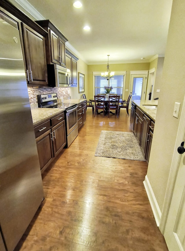 179 Trade Wind Dr, Fort Oglethorpe, GA 30742 - kitchen with stainless steel appliances, dark brown cabinetry, ornamental molding, a chandelier, and tasteful backsplash