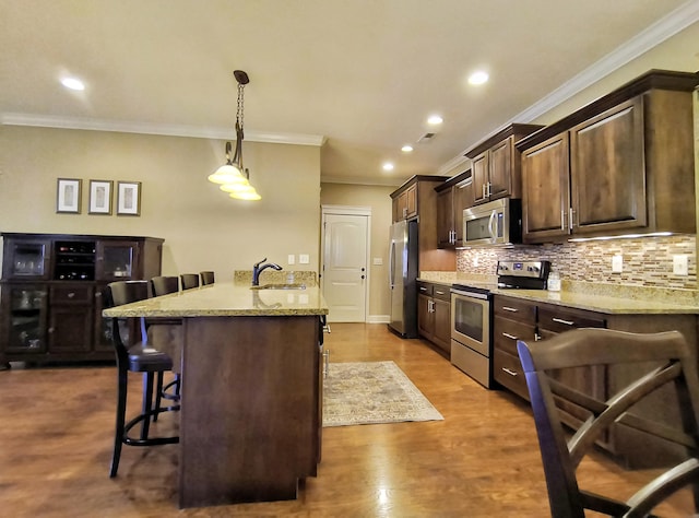 179 Trade Wind Dr, Fort Oglethorpe, GA 30742 - kitchen featuring appliances with stainless steel finishes, a breakfast bar area, crown molding, dark brown cabinets, and a peninsula
