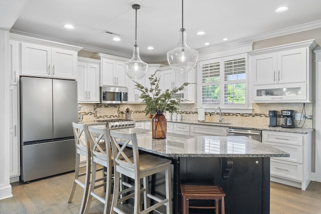 3528 Morning Dew Cv, Apison, TN 37302 - kitchen featuring stainless steel appliances, white cabinetry, ornamental molding, a kitchen island, and light wood-type flooring