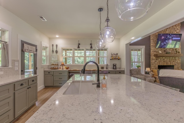 508 Chattanooga Rd, Cohutta, GA 30710 - kitchen featuring gray cabinetry, light stone countertops, hanging light fixtures, light wood finished floors, and a stone fireplace