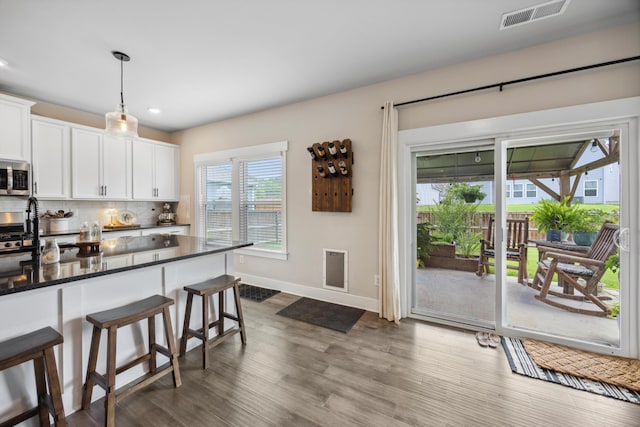 8517 Kensley Ln, Hixson, TN 37343 - kitchen featuring a kitchen bar, stainless steel microwave, backsplash, white cabinets, and recessed lighting