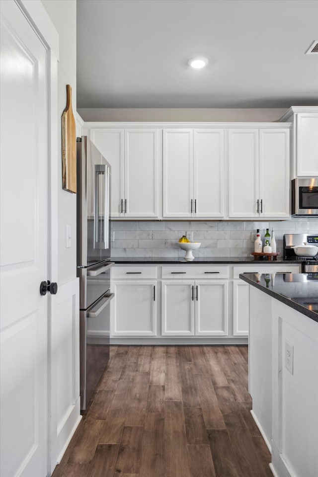 8517 Kensley Ln, Hixson, TN 37343 - kitchen with appliances with stainless steel finishes, dark countertops, white cabinets, dark wood-type flooring, and backsplash