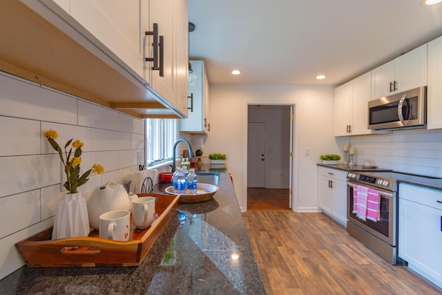 136 Cochran Dr NE, Dalton, GA 30721 - kitchen with appliances with stainless steel finishes, dark countertops, white cabinetry, recessed lighting, and backsplash