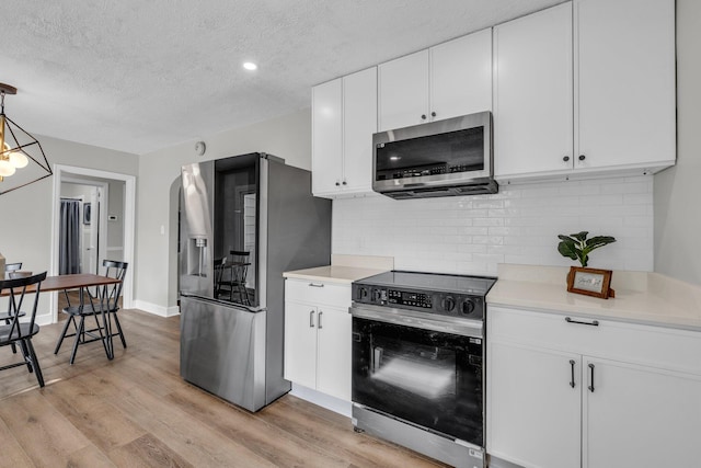 1610 Truman Ave, Chattanooga, TN 37412 - kitchen featuring appliances with stainless steel finishes, decorative backsplash, light wood finished floors, light countertops, and a textured ceiling