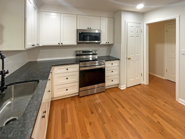 8127 Blue Spruce Dr, Hixson, TN 37343 - kitchen with stainless steel appliances, tasteful backsplash, light wood finished floors, white cabinets, and dark stone countertops