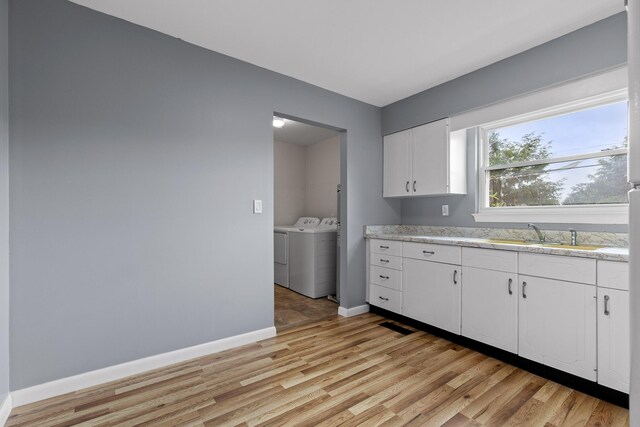 608 Maple Ln, Chattanooga, TN 37412 - kitchen with washing machine and clothes dryer, light wood finished floors, and white cabinets