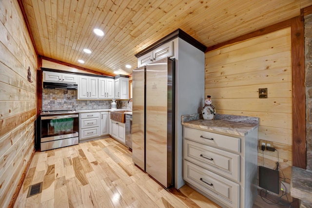 1590 Jackson Point Rd, Sewanee, TN 37375 - kitchen with stainless steel appliances, under cabinet range hood, wooden walls, vaulted ceiling, and light wood-type flooring