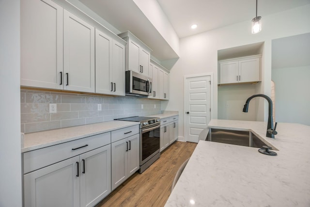 LOT3 Ari Ln, Chattanooga, TN 37421 - kitchen featuring appliances with stainless steel finishes, decorative backsplash, light wood-type flooring, hanging light fixtures, and light stone countertops