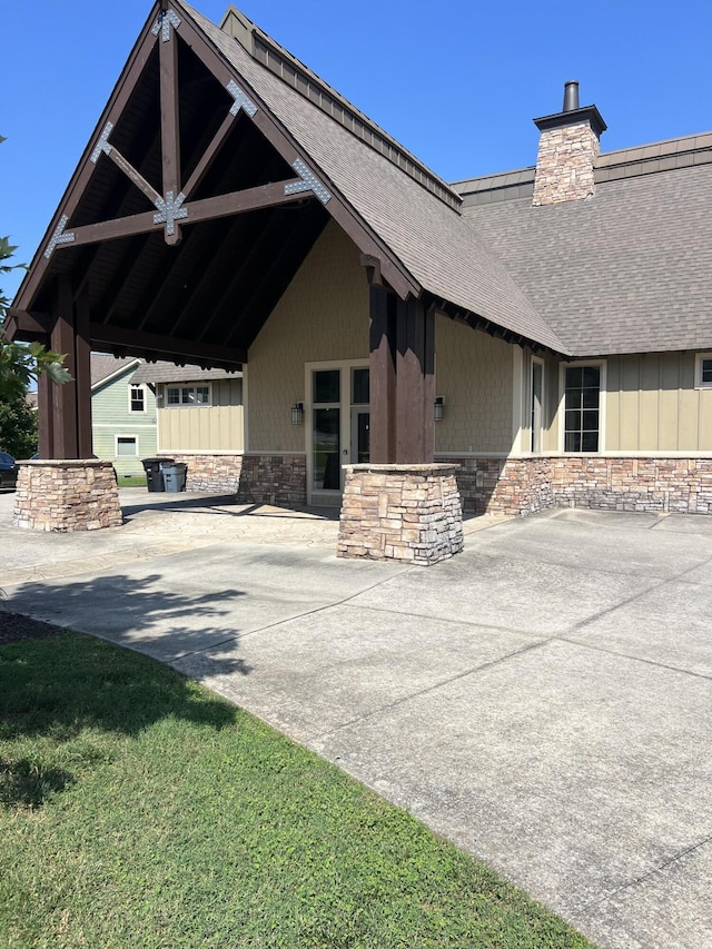 3309 Grassy Fields Ln, Apison, TN 37302 - view of exterior entry with stone siding, a shingled roof, and a chimney