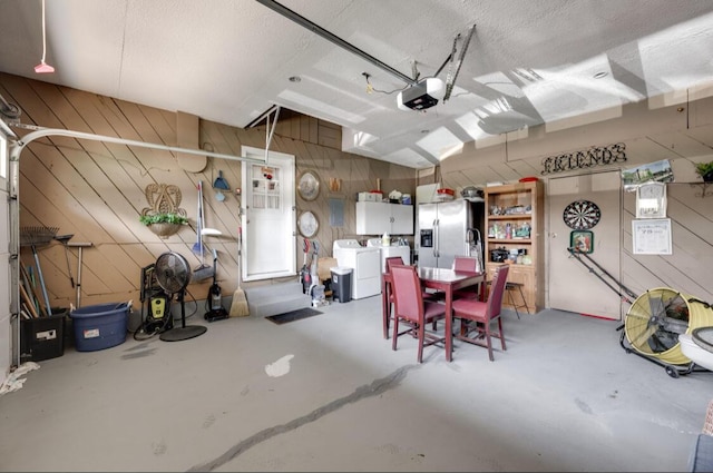 1339 Woodmore Ln, Chattanooga, TN 37411 - garage with washer and clothes dryer, a garage door opener, stainless steel fridge with ice dispenser, and wood walls