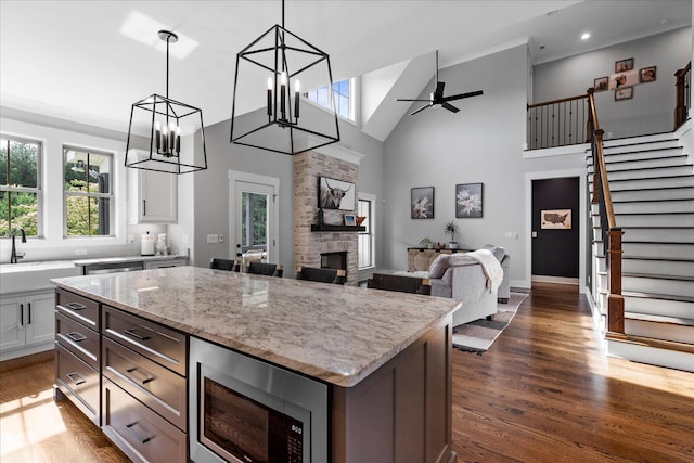 12951 Blakeslee Dr, Soddy Daisy, TN 37379 - kitchen with stainless steel microwave, high vaulted ceiling, dark wood-type flooring, light stone counters, and open floor plan