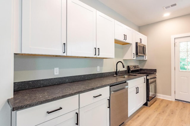 409 Hall St, Lafayette, GA 30728 - kitchen with stainless steel appliances, white cabinets, light wood-type flooring, dark stone counters, and recessed lighting