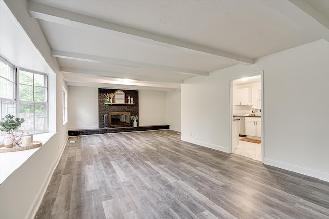 3706 Altamira Dr, Chattanooga, TN 37412 - unfurnished living room with beamed ceiling, light wood-type flooring, a fireplace, and a textured ceiling