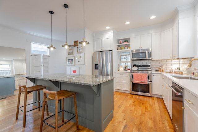 661 E 16th St, Chattanooga, TN 37408 - kitchen with appliances with stainless steel finishes, tasteful backsplash, white cabinetry, a kitchen breakfast bar, and a kitchen island