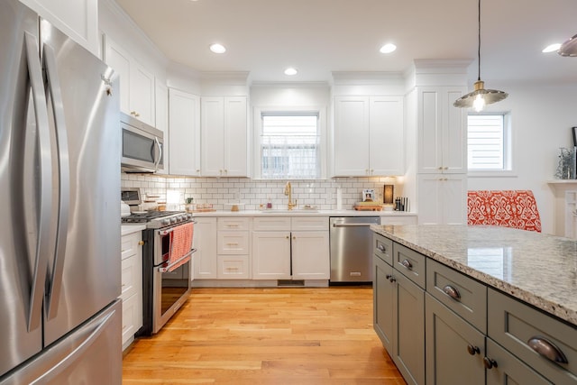 661 E 16th St, Chattanooga, TN 37408 - kitchen featuring appliances with stainless steel finishes, tasteful backsplash, white cabinetry, light wood-style flooring, and pendant lighting