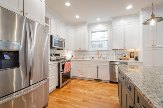 661 E 16th St, Chattanooga, TN 37408 - kitchen with stainless steel appliances, white cabinetry, light wood finished floors, tasteful backsplash, and crown molding