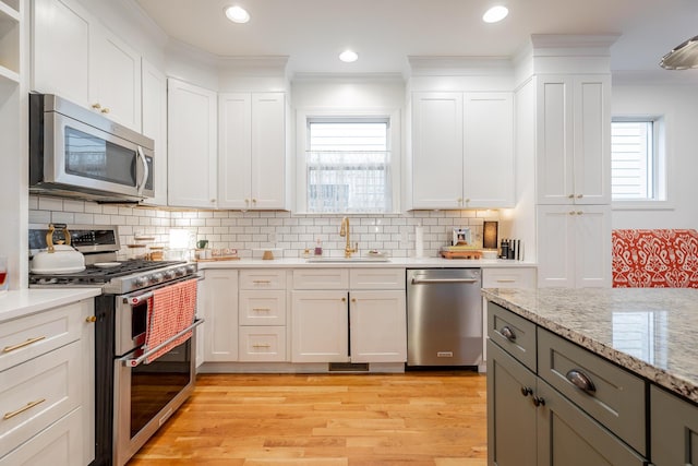 661 E 16th St, Chattanooga, TN 37408 - kitchen featuring stainless steel appliances, crown molding, white cabinets, light wood finished floors, and decorative backsplash