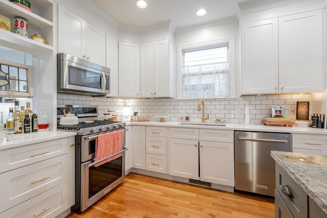 661 E 16th St, Chattanooga, TN 37408 - kitchen with appliances with stainless steel finishes, crown molding, white cabinets, tasteful backsplash, and light wood-type flooring