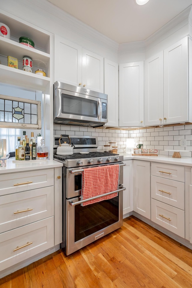 661 E 16th St, Chattanooga, TN 37408 - kitchen with appliances with stainless steel finishes, light countertops, backsplash, white cabinets, and crown molding