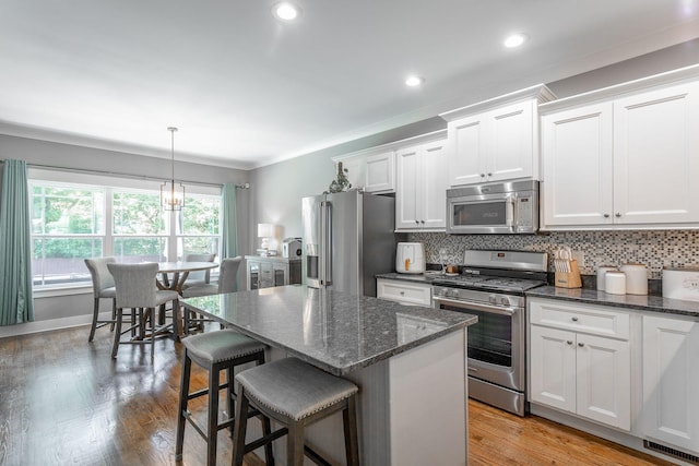 1023 Givens Rd, Chattanooga, TN 37421 - kitchen featuring stainless steel appliances, tasteful backsplash, a breakfast bar area, white cabinets, and a kitchen island