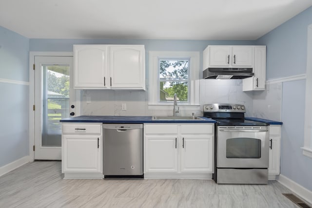 3018 14th Ave, Chattanooga, TN 37407 - kitchen featuring appliances with stainless steel finishes, under cabinet range hood, dark countertops, tasteful backsplash, and white cabinetry