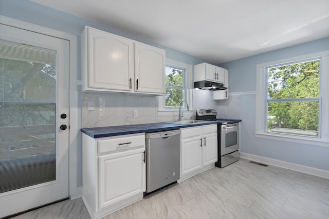 3018 14th Ave, Chattanooga, TN 37407 - kitchen featuring stainless steel appliances, under cabinet range hood, dark countertops, white cabinets, and tasteful backsplash