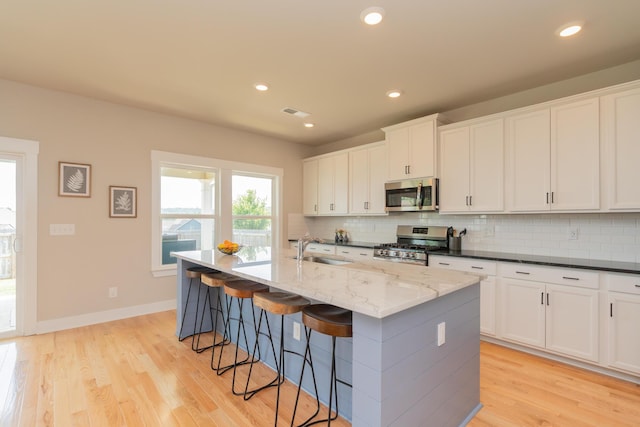 3328 Prairie Range Ln, Apison, TN 37302 - kitchen with stainless steel appliances, backsplash, a kitchen bar, light wood finished floors, and a kitchen island with sink