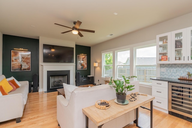 3328 Prairie Range Ln, Apison, TN 37302 - living room with wine cooler, light wood-style flooring, a ceiling fan, a fireplace, and a bar
