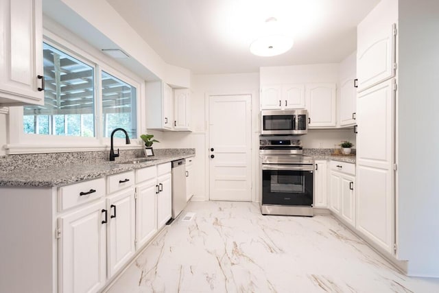 3517 Connelly Ln, Chattanooga, TN 37412 - kitchen featuring appliances with stainless steel finishes, light marble finish flooring, white cabinetry, and light stone counters