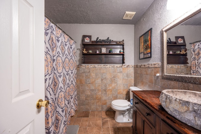 6220 Hunter Valley Rd, Ooltewah, TN 37363 - full bath with vanity, tile walls, a textured ceiling, a textured wall, and stone finish flooring