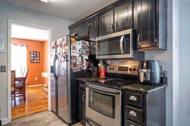 6220 Hunter Valley Rd, Ooltewah, TN 37363 - kitchen with appliances with stainless steel finishes, dark cabinetry, light wood-style floors, and a textured ceiling