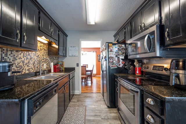 6220 Hunter Valley Rd, Ooltewah, TN 37363 - kitchen featuring stainless steel appliances, dark cabinetry, light wood finished floors, decorative backsplash, and a textured ceiling
