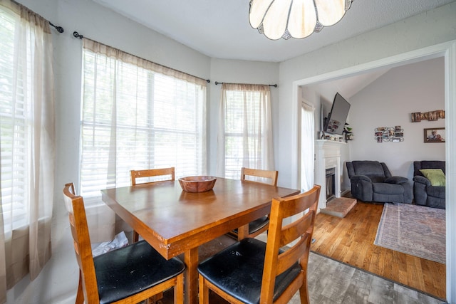 6220 Hunter Valley Rd, Ooltewah, TN 37363 - dining area featuring a fireplace with raised hearth, wood finished floors, a chandelier, and lofted ceiling